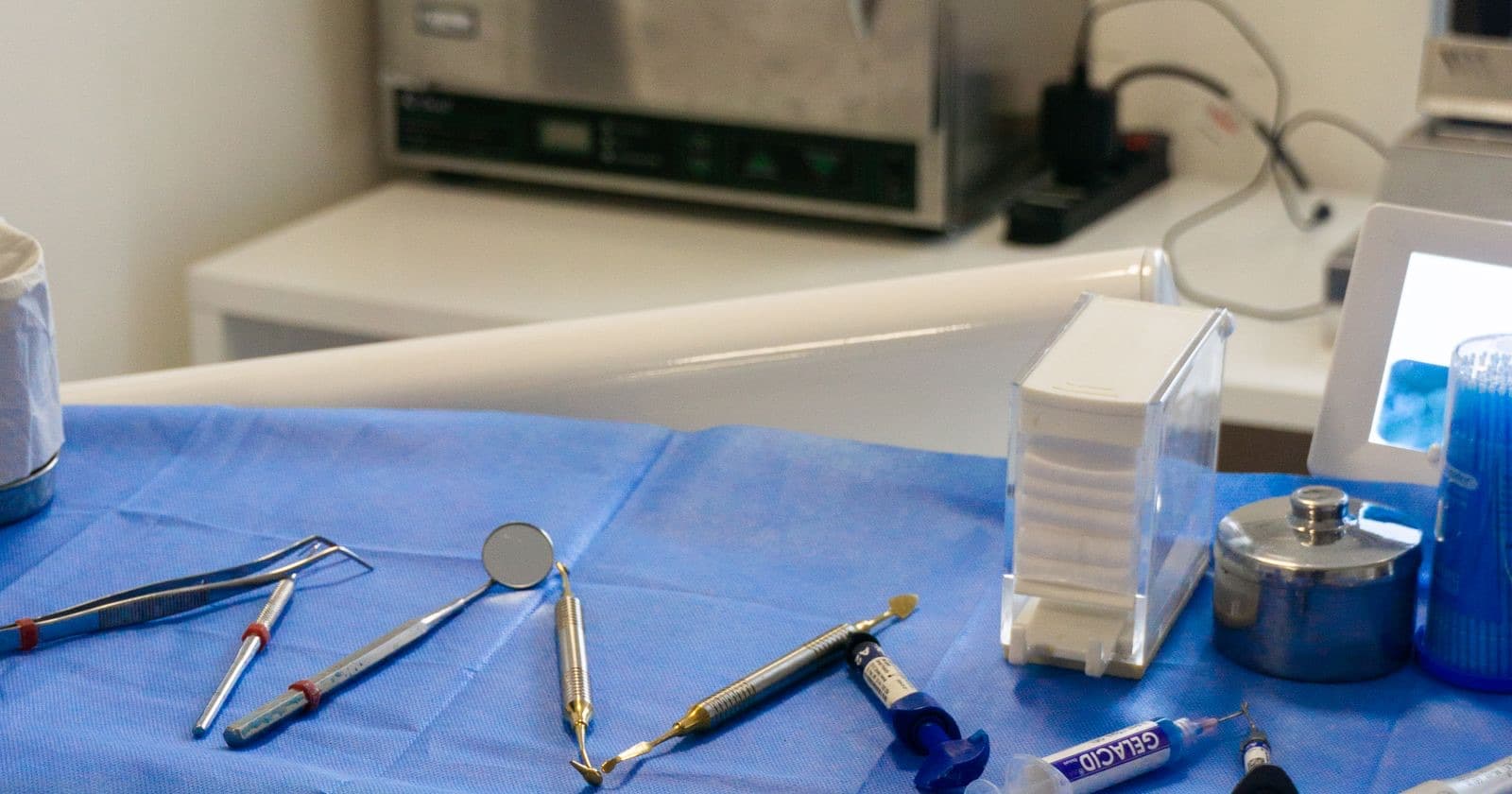 Dental instruments, mirror and handpieces laid on a blue sterile tray in a dental surgery