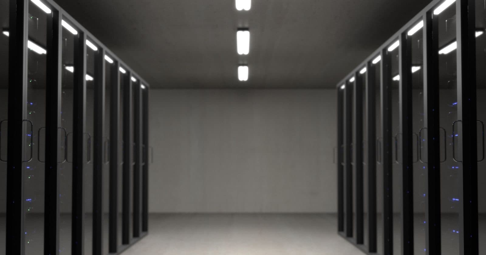 Empty server room corridor with racks of equipment lit by ceiling strip lights
