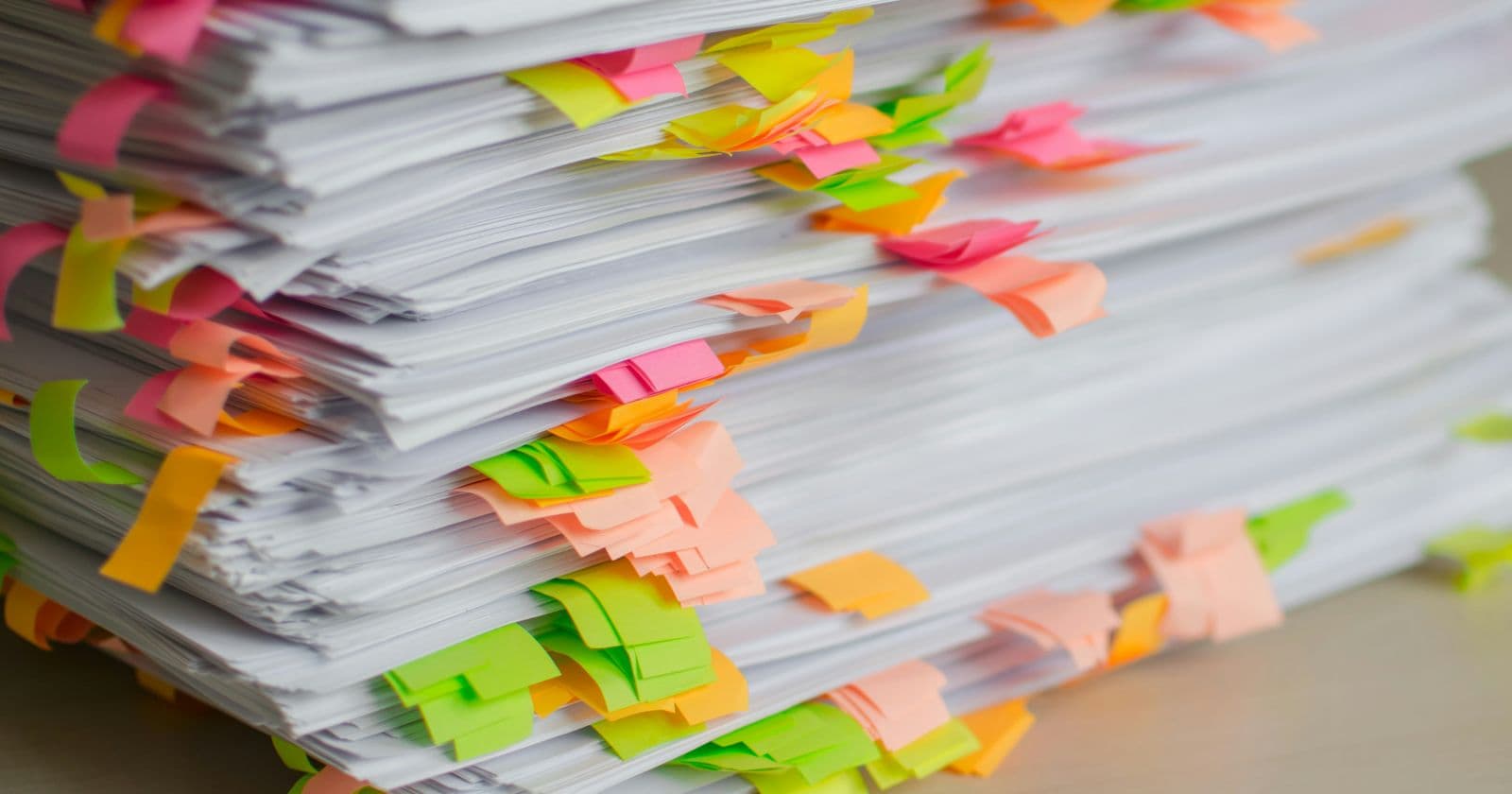 Stock photo: Tall stack of printed papers marked with pink, green and orange sticky tabs on a desk