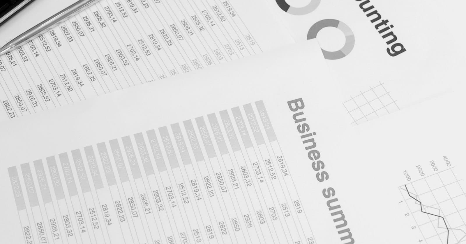 Printed accounting business summary reports with tables, charts and a calculator on a desk