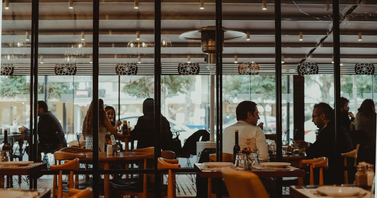 Diners seated at tables inside a busy restaurant seen through large glass windows